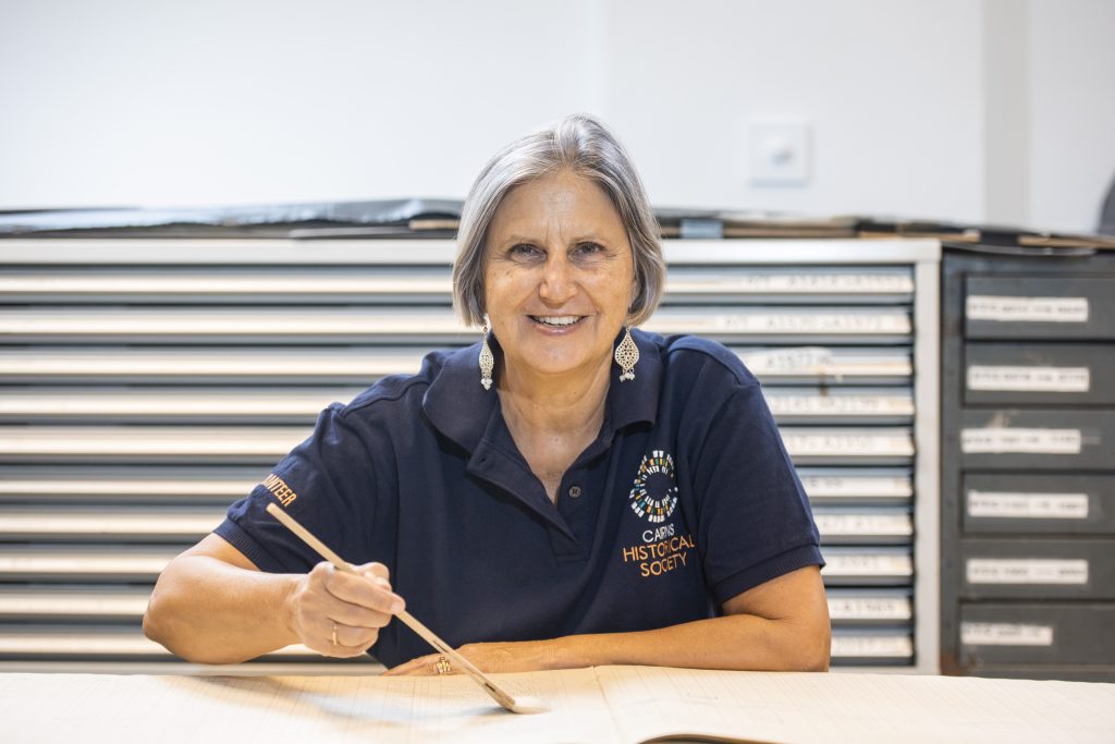 Woman seated in front of a map drawer in the Research Centre preserving a book